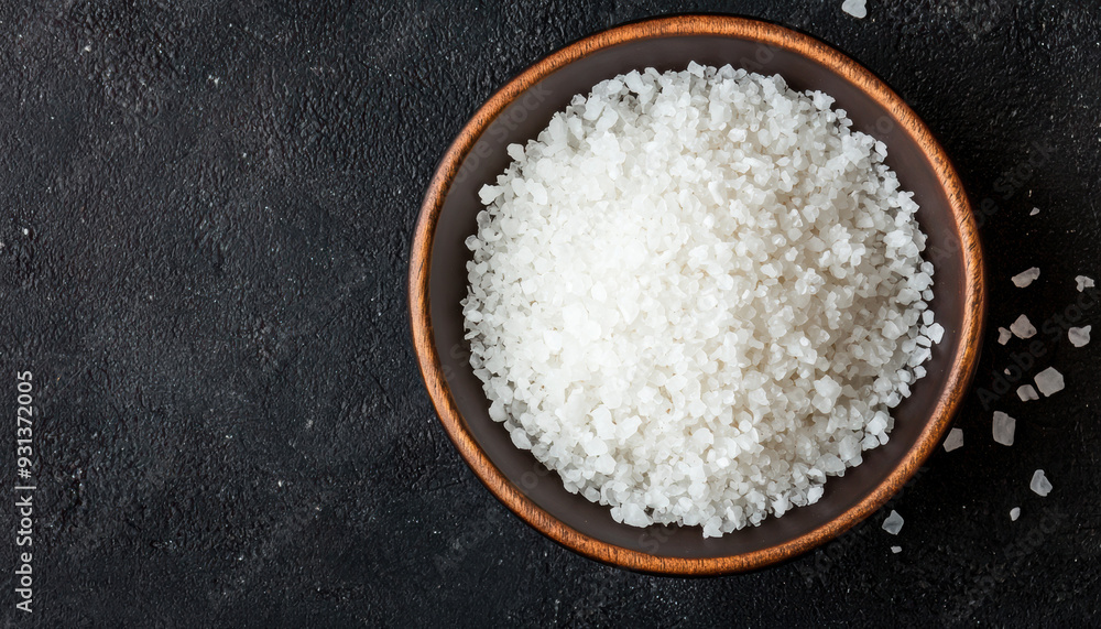 Top view of a bowl of coarse sea salt on a dark textured background, ideal for culinary, cooking, and seasoning concepts. Top view of a bowl of coarse sea salt on a dark textured background, ideal for culinary, cooking, and seasoning concepts.