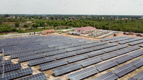 Aerial rotating reverse overview of solar PV power station with Battery Energy Storage System and solar car park photo