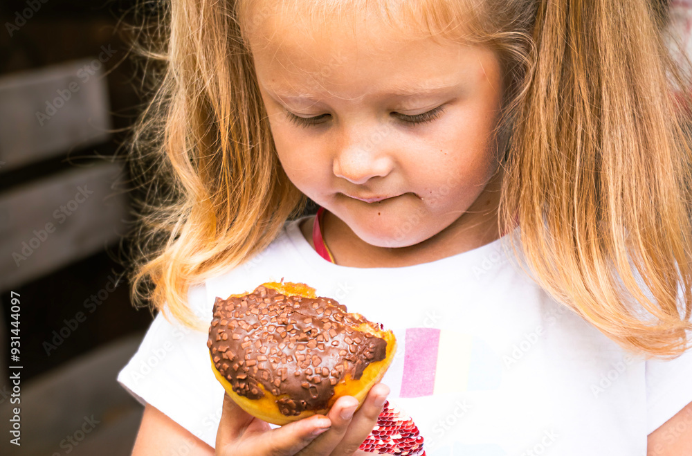 Little blonde girl eating chocolate donut. junk food, sweetness, children's joy. Little blonde girl eating chocolate donut. junk food, sweetness, children's joy.