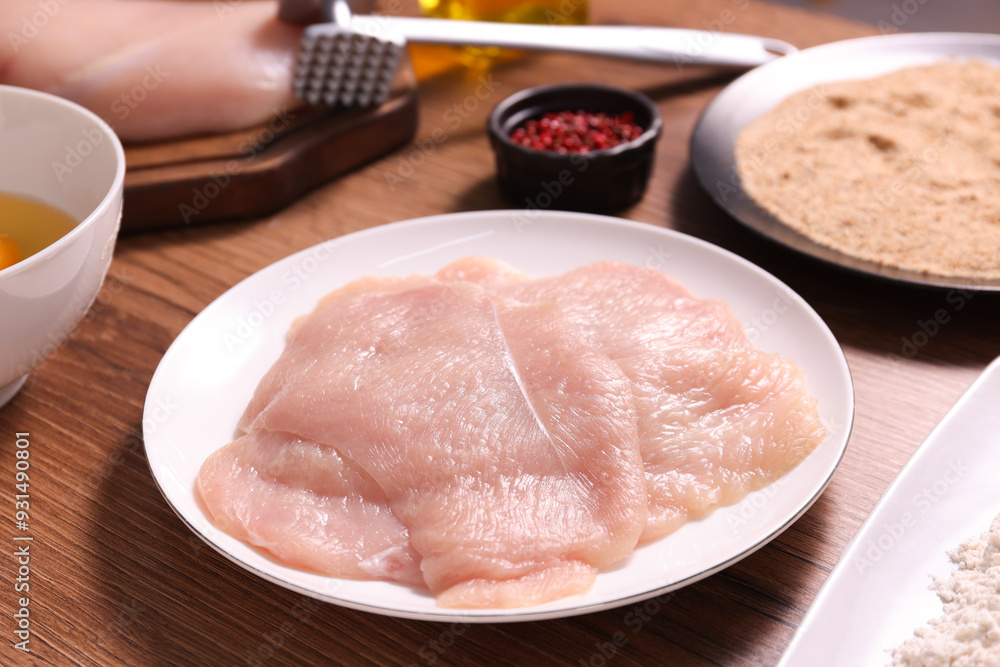 Making schnitzel. Plate with raw meat on wooden table, closeup Making schnitzel. Plate with raw meat on wooden table, closeup