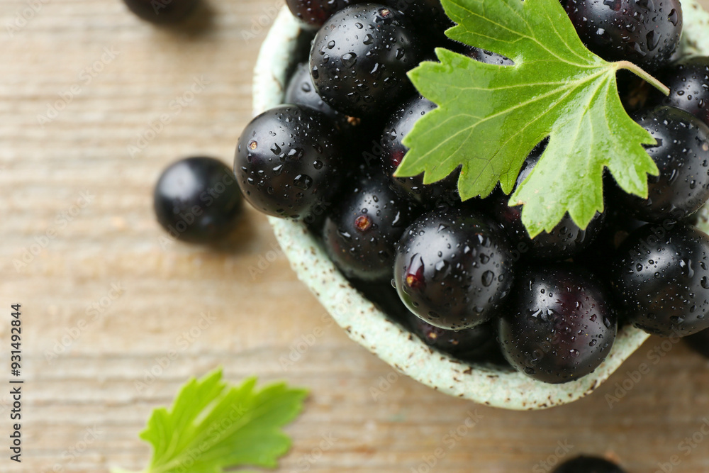 Fresh ripe black currant berries and leaves on wooden table, closeup Fresh ripe black currant berries and leaves on wooden table, closeup