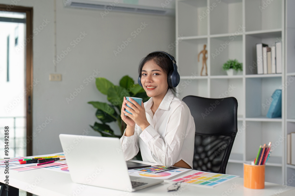 Young Graphic Designer Working at Modern Office Desk with Laptop, Color Swatches, and Headphones Young Graphic Designer Working at Modern Office Desk with Laptop, Color Swatches, and Headphones