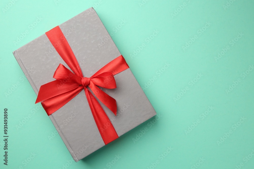 Book tied with red ribbon on green background, top view with space for text. Perfect gift Book tied with red ribbon on green background, top view with space for text. Perfect gift