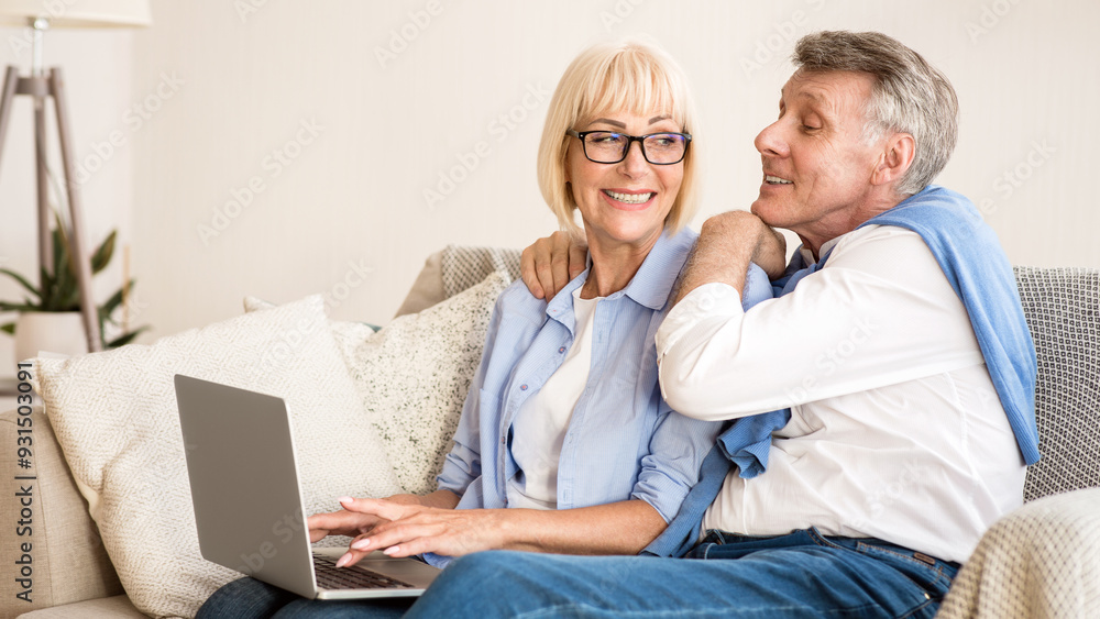 Happy senior couple websurfing on laptop and spending weekend together at home Happy senior couple websurfing on laptop and spending weekend together at home