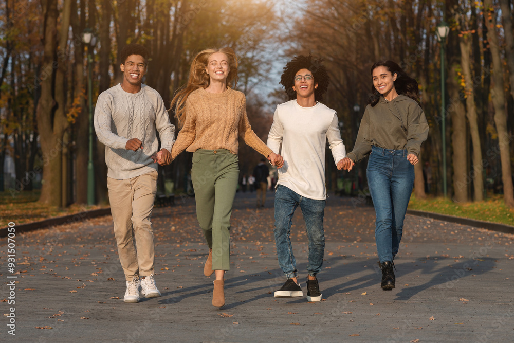 Fototapeta premium Crazy multiracial teen friends running towards camera, public park background, panorama