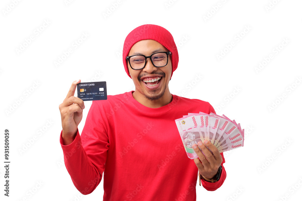 Happy Indonesian man wearing a red long-sleeve shirt and red beanie, holding a credit card and money during Indonesia's Independence Day celebration on August 17, isolated on a white background Happy Indonesian man wearing a red long-sleeve shirt and red beanie, holding a credit card and money during Indonesia's Independence Day celebration on August 17, isolated on a white background