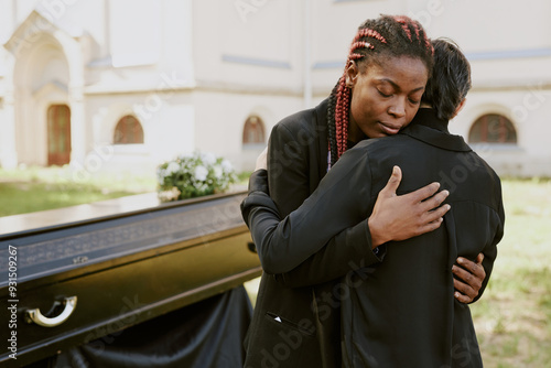 Foto African American woman hugging her Caucasian mom and crying at funeral