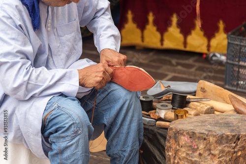 Close-up detail of the hands of a cobbler mending a shoe in the open air at the medieval market in Hondarribia.