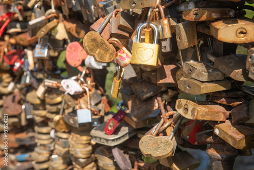 background of fence on bridge filled with metal closed love locks of couples  photo