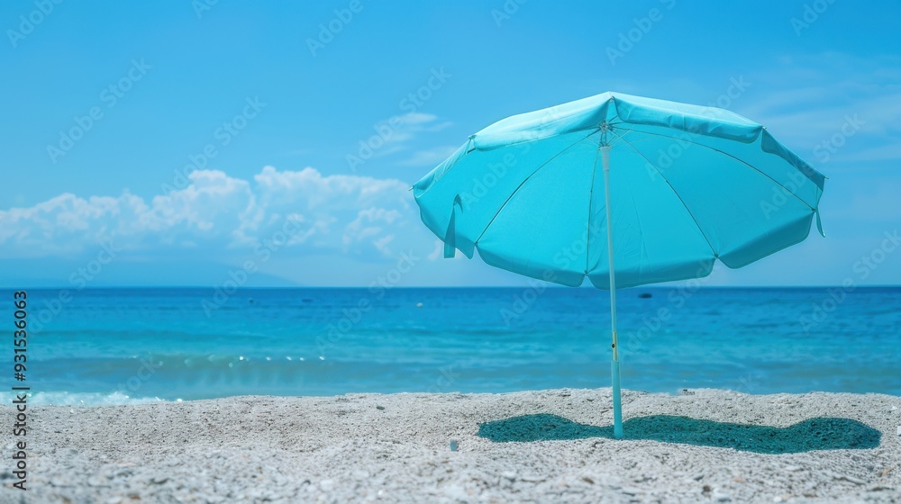A light blue umbrella casting shade on a sunny beach, with the ocean in the background A light blue umbrella casting shade on a sunny beach, with the ocean in the background