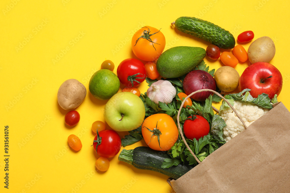 Delivery of vegetarian products. Paper bag with different vegetables and fruits on yellow background, top view Delivery of vegetarian products. Paper bag with different vegetables and fruits on yellow background, top view