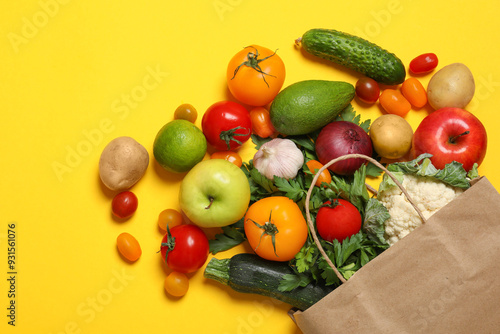 Fototapeta Naklejka Na Ścianę i Meble -  Delivery of vegetarian products. Paper bag with different vegetables and fruits on yellow background, top view