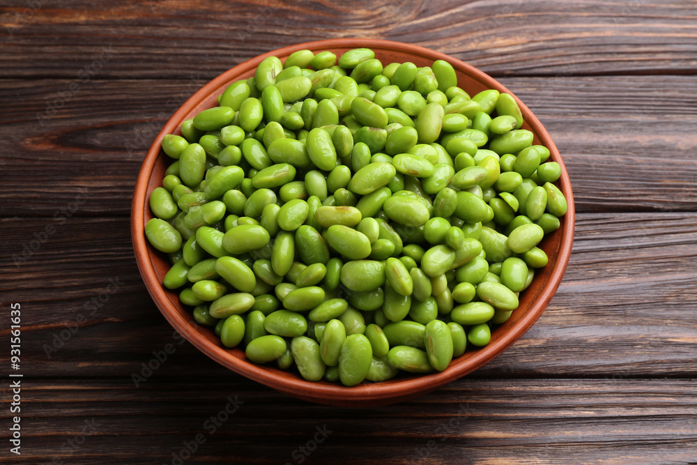 Raw green edamame soybeans in bowl on wooden table Raw green edamame soybeans in bowl on wooden table