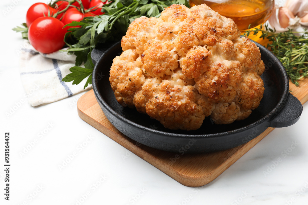 Delicious baked cauliflower in baking dish and products on white table, closeup Delicious baked cauliflower in baking dish and products on white table, closeup