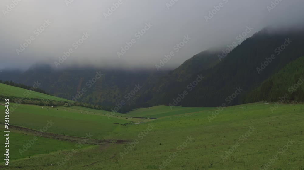 Moving clouds unveiling a lush mountain valley landscape Moving clouds unveiling a lush mountain valley landscape