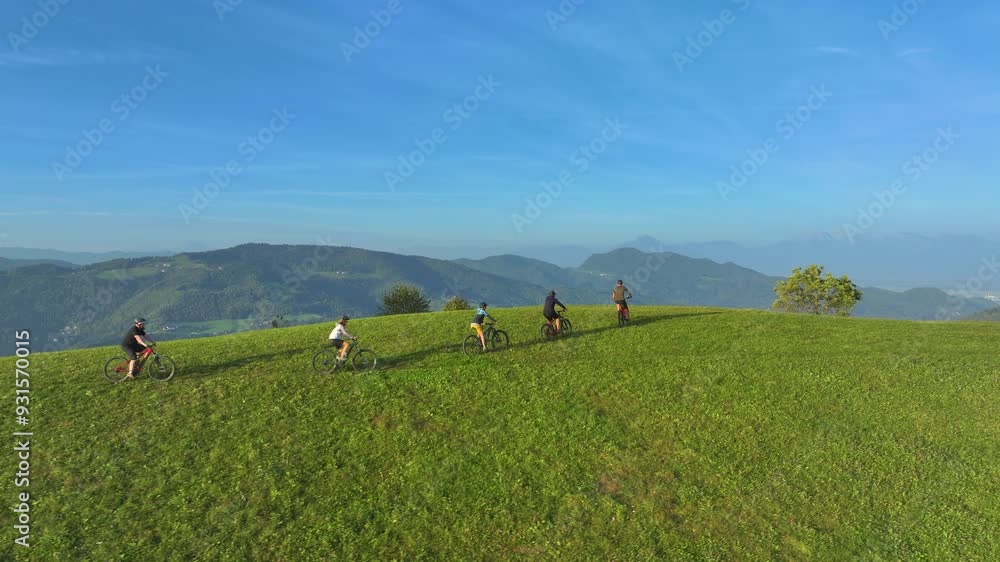 AERIAL: Mountain bikers celebrate reaching the top of hill with a stunning view of green hilly landscape and distant mountains. Nice autumn day for cycling and exploring the countryside with friends. AERIAL: Mountain bikers celebrate reaching the top of hill with a stunning view of green hilly landscape and distant mountains. Nice autumn day for cycling and exploring the countryside with friends.