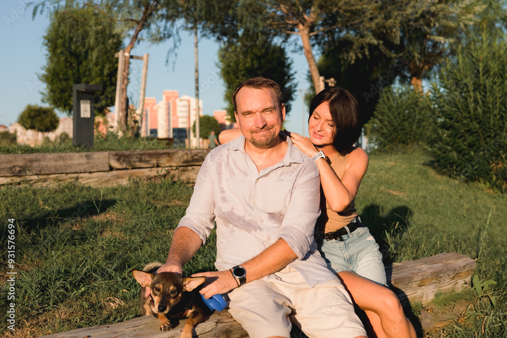 Fototapeta premium A happy smiling couple walking, hugging and kissing in park on late summer sunset