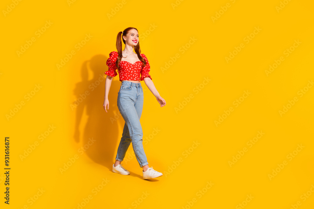 Full size photo of pretty young girl walking model wear trendy red outfit isolated on yellow color background Full size photo of pretty young girl walking model wear trendy red outfit isolated on yellow color background