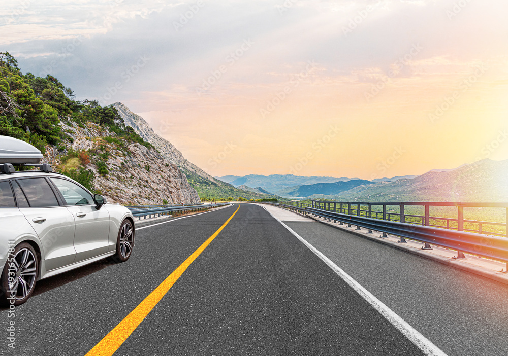 The car is driving along the highway surrounded by picturesque nature.
