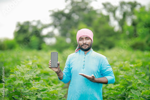 happy young Indian farmer using smart phone