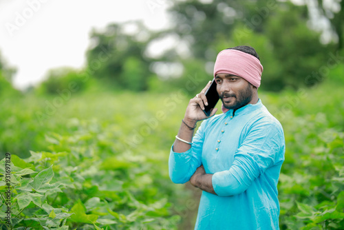 happy young Indian farmer using smart phone