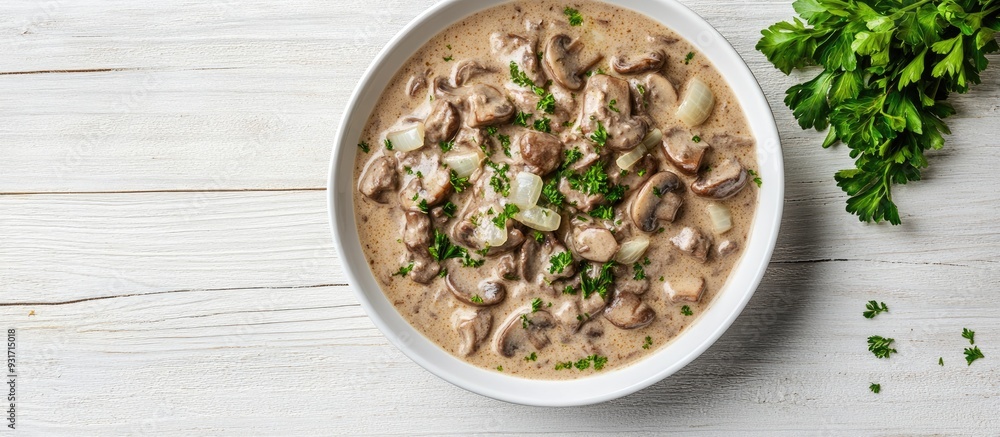 Homemade creamy beef stroganoff with mushroom slices and onions served in a bowl captured from above on white wood with copy space alongside Selective Focus Focus on the dish Homemade creamy beef stroganoff with mushroom slices and onions served in a bowl captured from above on white wood with copy space alongside Selective Focus Focus on the dish