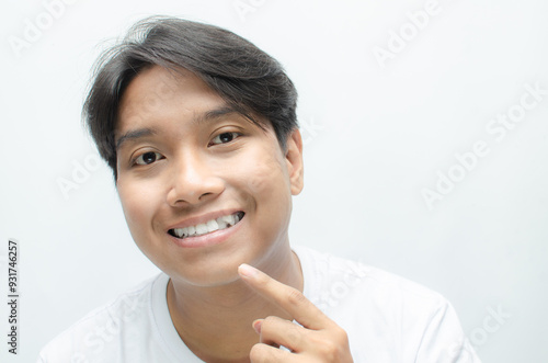 young asian man smiling and showing his crooked teeth isolated over white background. dracula teeth and bucktooth concept. overlapping teeth of man photo