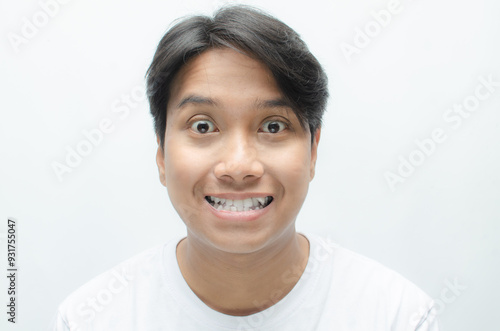 young asian man smiling and showing his crooked teeth isolated over white background. dracula teeth and bucktooth concept. overlapping teeth of man photo