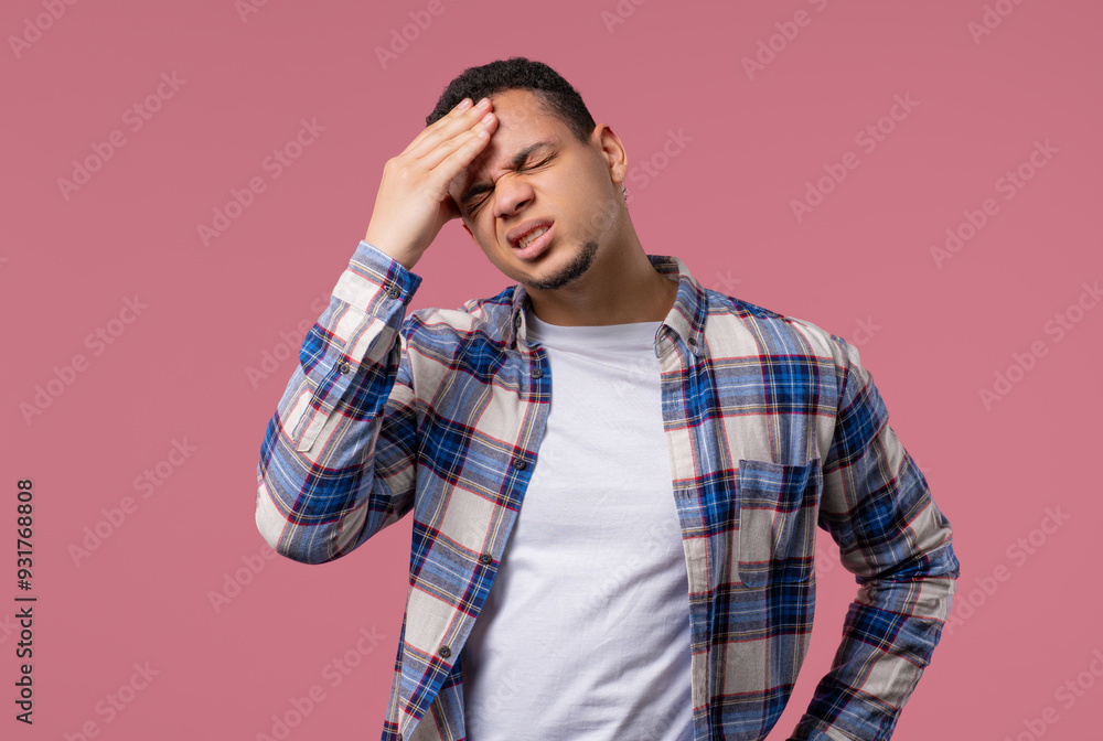 Young african man having headache, studio portrait.Guy puts hand on head, pink Young african man having headache, studio portrait.Guy puts hand on head, pink