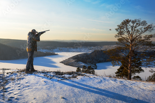 Hunter shooting bird at winter snowy nature photo