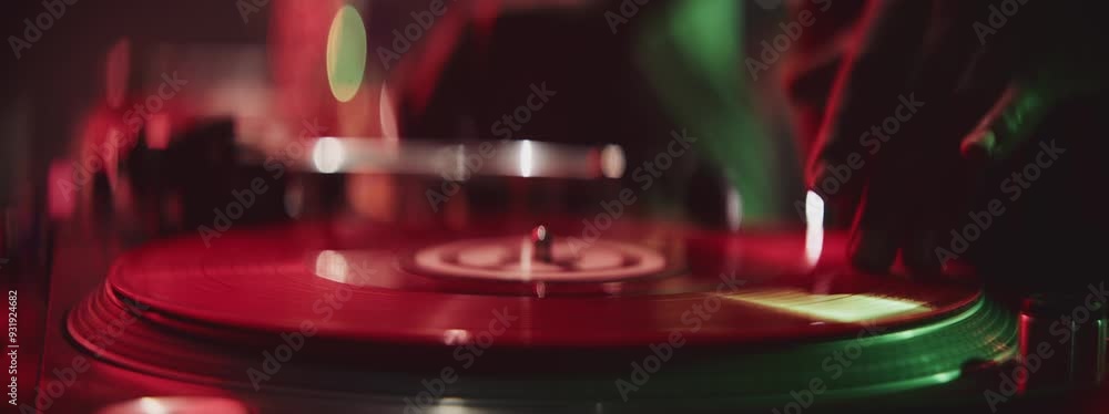 Extreme close-up view of a professional dj's hand scratching vinyl record on turntable on a party under spotlights Extreme close-up view of a professional dj's hand scratching vinyl record on turntable on a party under spotlights