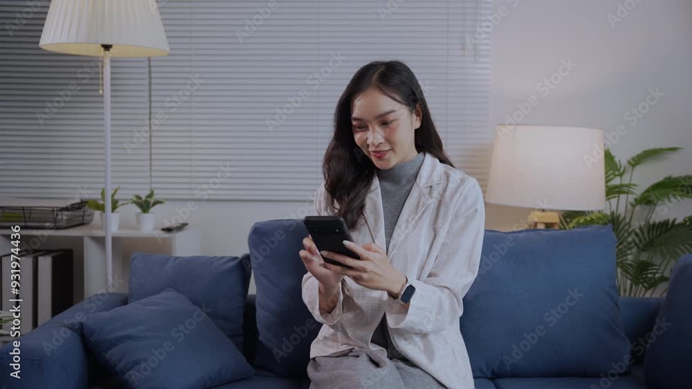 Young woman sitting on a couch, browsing social media on her smartphone, enjoying a relaxed evening at home Young woman sitting on a couch, browsing social media on her smartphone, enjoying a relaxed evening at home