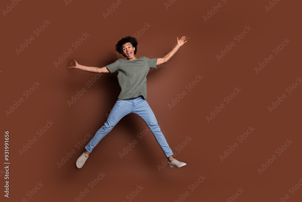 Full size photo of nice young guy excited jump wear trendy khaki outfit isolated on brown color background Full size photo of nice young guy excited jump wear trendy khaki outfit isolated on brown color background