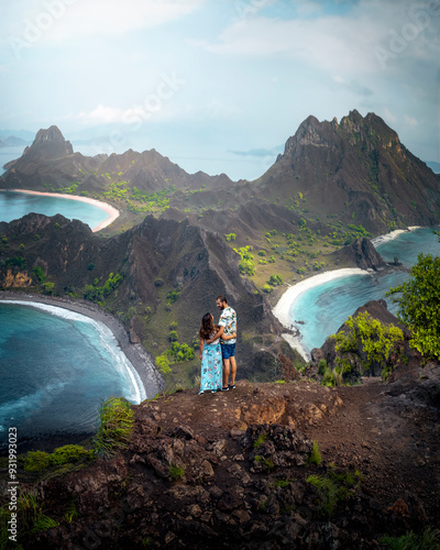 Couple on Mountain Peak Overlooking Serene Coastal Landscape in Palau Palar, Indonesia photo