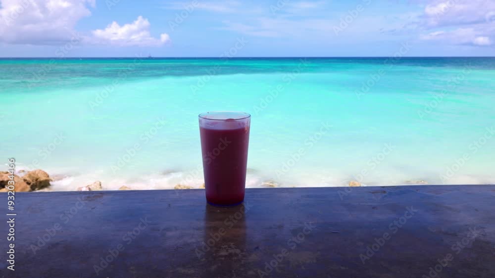 Close up view of alcoholic cocktail on bar counter with view of Caribbean waves and sandy beach on Aruba. Close up view of alcoholic cocktail on bar counter with view of Caribbean waves and sandy beach on Aruba.