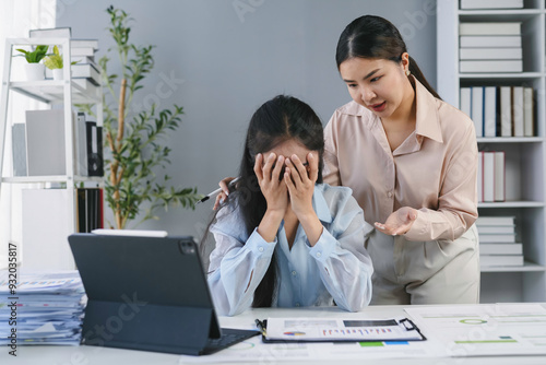 Manager is scolding her employee who is covering her face with her hands, feeling stressed and ashamed