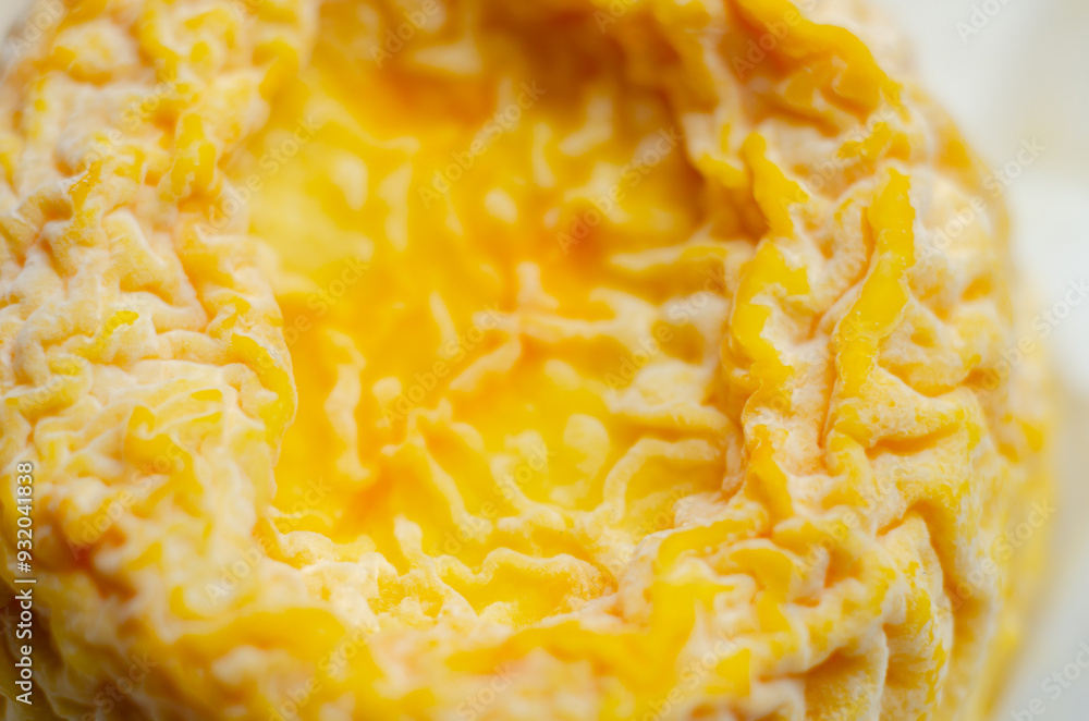 A yellow cheese is sitting in a paper wrapper A yellow cheese is sitting in a paper wrapper