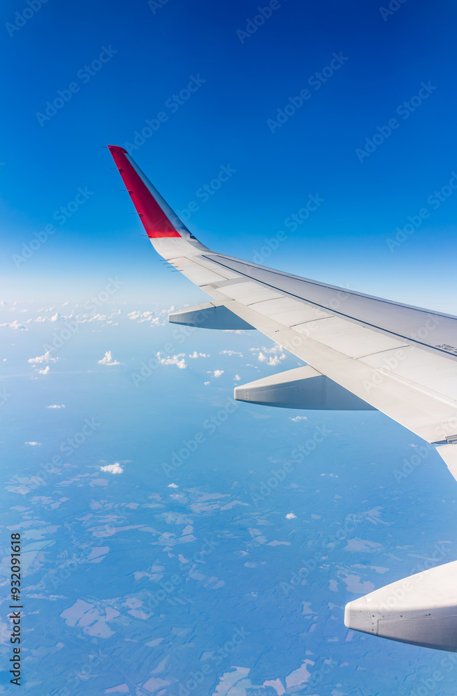 Fototapeta premium View from the airplane window at a beautiful cloudy sky and the airplane wing
