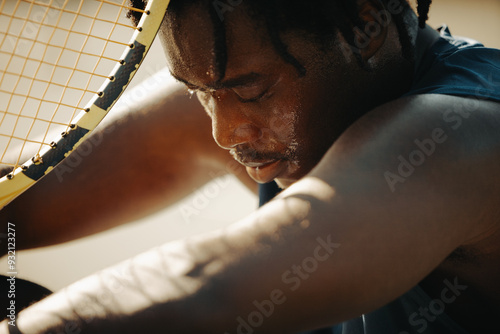 Картината върху платно Man resting with tennis racket, looking sad in sunlight after a challenging game