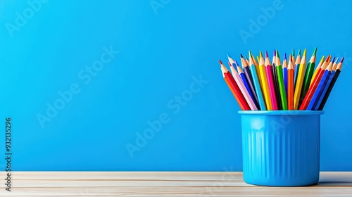 Back-to-school style banner with colorful pencils in a blue cup on a wooden surface against a vibrant blue background.
