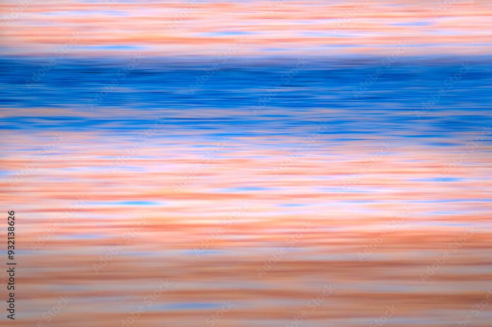 Obraz premium A motion blur applied to an ocean shore at sunset. The combination of beautiful blue and pale apricot horizontal lines invoke a sense of calm and serenity. Background for type and graphics.