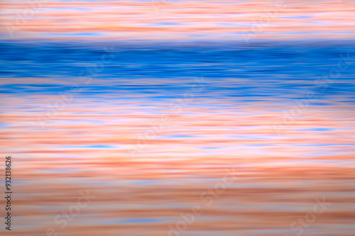 A motion blur applied to an ocean shore at sunset. The combination of beautiful blue and pale apricot horizontal lines invoke a sense of calm and serenity. Background for type and graphics.