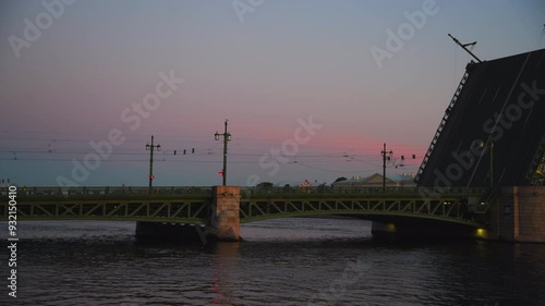 Side view of open bascule bridge with some buildings on Vasilyevsky isaland embankment at sunrise in Saint Petersburg, Russia. Romantic twilight sky. Real time video. Travel in Russia theme. photo