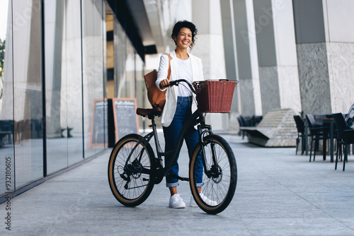 Smiling woman with bicycle and backpack in urban European city photo