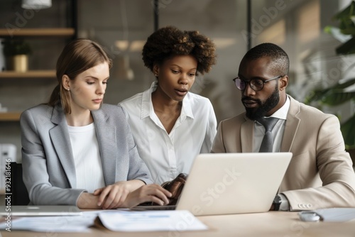 A diverse team of professionals engages in a collaborative discussion around a laptop in a contemporary workspace.