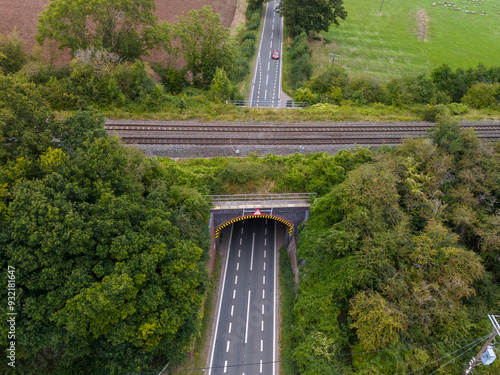 Aerial view of a countryside road passing under a railway bridge