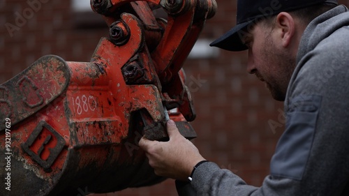 Construction worker attaches bucket to backhoe excavtor bucket