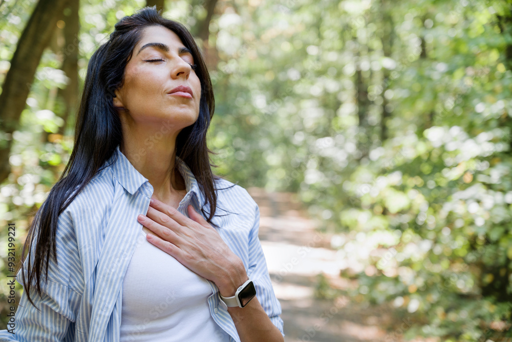 Relaxed woman breathing fresh air in a green summer forest and making breathing exercises Relaxed woman breathing fresh air in a green summer forest and making breathing exercises