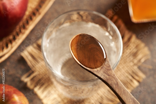A spoonful of apple cider vinegar above a glass of water