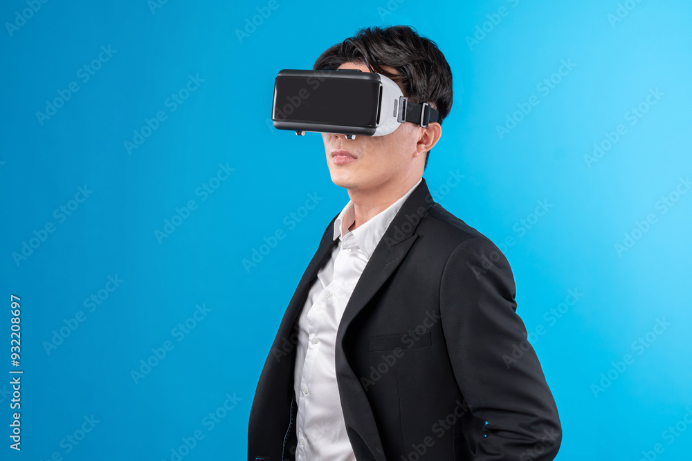 Smiling Asian businessman looking thorough VR connecting to business world report in futuristic metaverse, analyzing innovation technology ads in virtual reality isolated blue copyspace. Contrivance. Smiling Asian businessman looking thorough VR connecting to business world report in futuristic metaverse, analyzing innovation technology ads in virtual reality isolated blue copyspace. Contrivance.